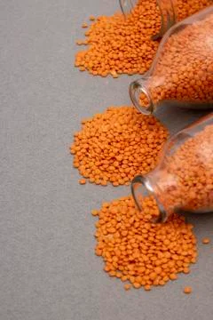 Red lentils scattered from three jars, vertical photo Stock Photos