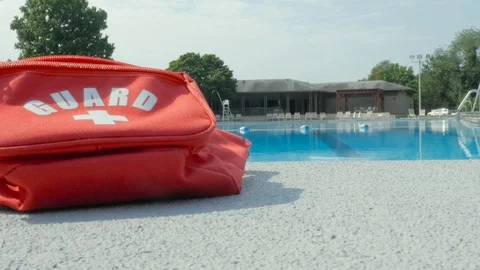 Red Lifeguard Fanny Pack on the Deck of a Public Pool Stock Footage 114635384