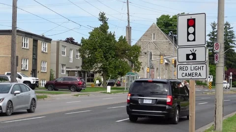 Red light camera sign next to a road with some traffic Stock Footage 283599643