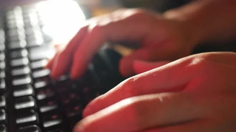 In the red light close up shot of person's hands typing on keyboard Stock Footage 134241946