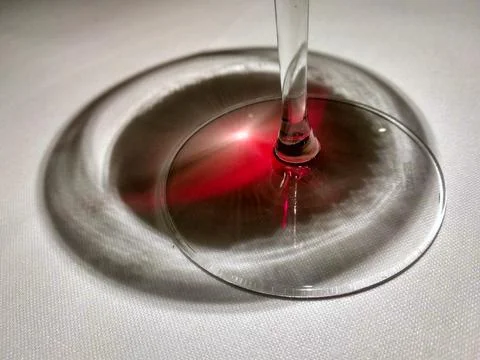 Red light passing through a glass of red wine and projecting onto the table Stock Photos