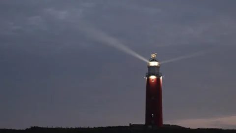Red Lighthouse at Dusk with Rotating Light Beam in Texel, Netherlands Stock Footage 337998576