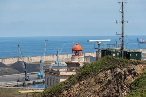 Red lighthouse lantern room, communications tower and heavy port cranes Stock Photos