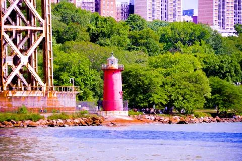 Red lighthouse next to a bridge in front of river with green background Stock Photos