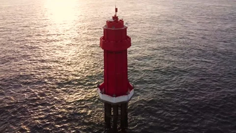 Red lighthouse in the ocean on sunset Stock Footage 156295840