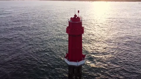 Red lighthouse in the ocean on sunset Stock Footage 156566044
