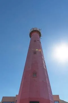 Red lighthouse standing behind a small house against a pur blue sunny and bri Stock-Fotos