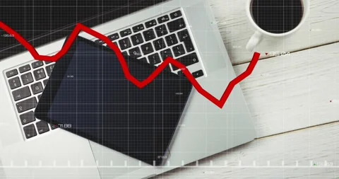 Red line graph animating across desk on live data while black tablet lying Stock Footage 328225354
