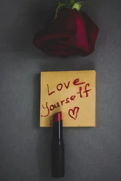 Red lipstick and a note with hand written text 'Love yourself', a heart symbol Stock Photos