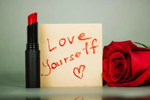 Red lipstick and note text Love yourself on cosmetic table. In love, romantic Stock Photos