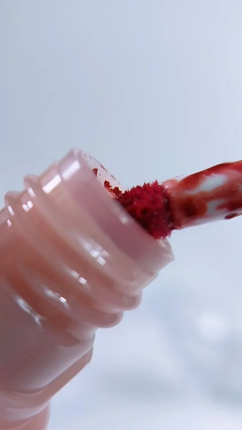 Red lipstick brush pulled from pink bottle in vertical front close up. Beau.. Video stock 340803768