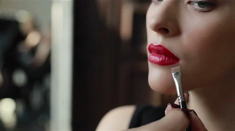 Red lipstick on lips of seductive young model. Professional make-up: finishing c Video stock 54636760