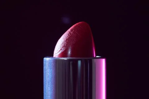 Red lipstick tip in macro, textured surface and glossy edge with moody studio Stock Photos