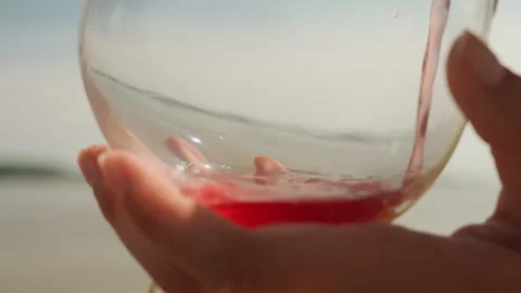 Red Liquid Being Poured Into Clear Glass Container Over Outdoor Background Stock Footage 345846770