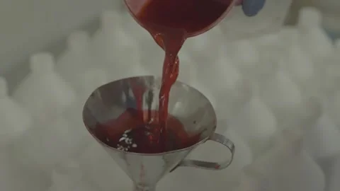 Red liquid being poured through a metal funnel in a laboratory. 스톡 동영상 330239910