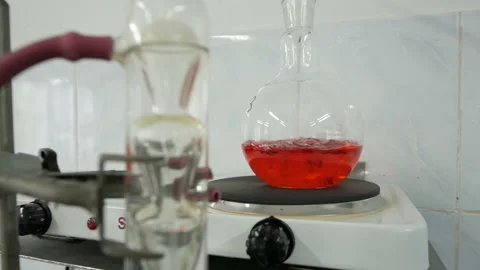 Red liquid is bubbling in a flask under laboratory conditions. Video stock 119304375