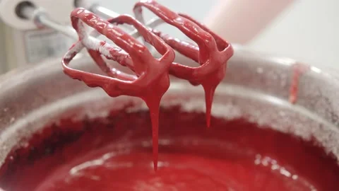 Red liquid dough drips from whisks of mixer into metal bowl Stock Footage 137932234