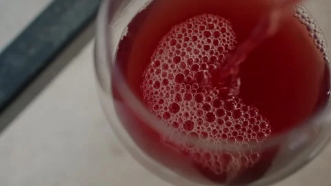 Red Liquid Pouring into Glass with Bubble Formation Close up showing foam Stock Footage 345853044