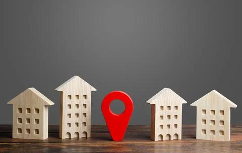 A red location indicator stands between residential buildings. Location and.. Stock Photos