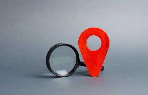 Red location pointer and a Magnifying glass on a gray background. Tourism a.. Stock Photos