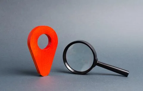 Red location pointer and a Magnifying glass on a gray background. Concept o.. Stock Photos