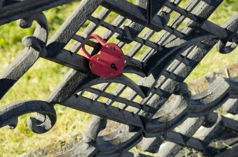 A red lock in the form of a heart attached to a fence. The symbol of the eter Stock Photos