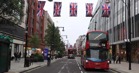 Red London buses under Union Jack flags on Oxford Street at dusk Stock Footage 321016295