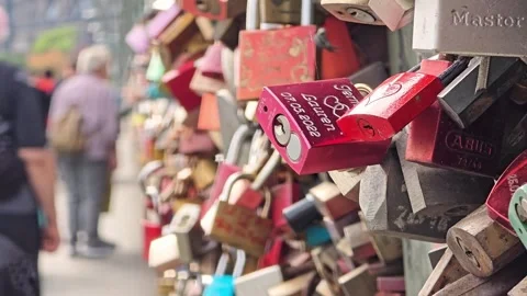 Red love locks on bridge railing with blurred people in background Stock Footage 345096955
