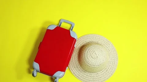 Red luggage and hat falling on yellow background Stock Footage 287437577