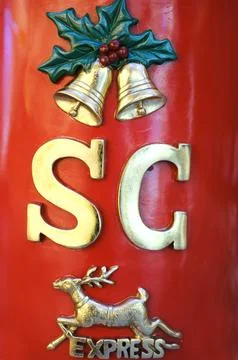 Red mailbox adorned with festive decorations, featuring golden letters and bells Stock Photos