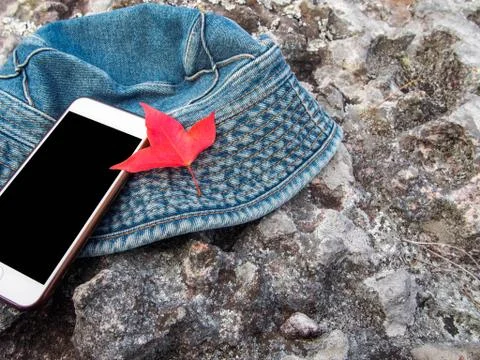 Red maple leaf ,cell phone and hat placed on the stone. Foto stock