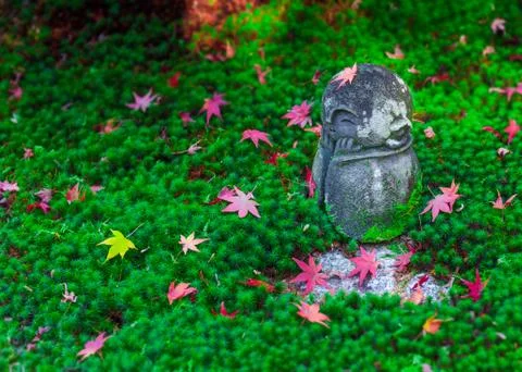 Red Maple leaf on head of Jizo sculpture doll in Japanese Garden, Enkoji Temple Stock-Fotos