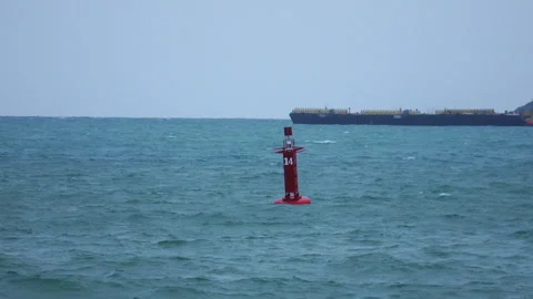 Red marine navigation marker buoy in open sea with cargo barge cruising Video stock 342916524