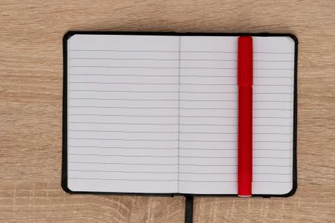 Red marker and open notebook on wooden desk Foto stock