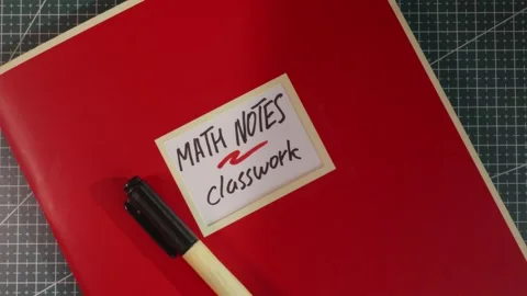 Red Math Notes Classwork workbook on wooden tabletop Stock Footage 341269408