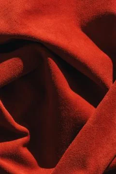 Red matte background of suede fabric, closeup. Velvet texture of seamless lea Stock Photos