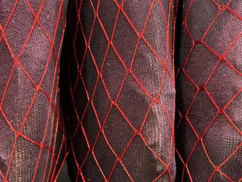 Red mesh surrounds bundled packages, weathered fabric encloses knotted diam.. Stock Photos