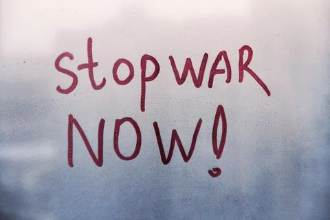 Red message call Stop war now are painted handwriting on blue window with rai Stock Photos
