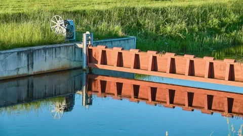 Red metal dam on a small river. Reflection in the water. Summer weather. Stock Footage 156820235