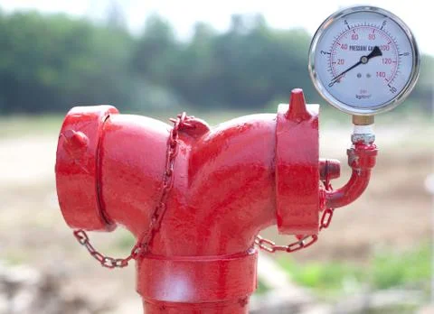Red metallic fire hydrant with pressure gauge or fire department connection o Stock Photos