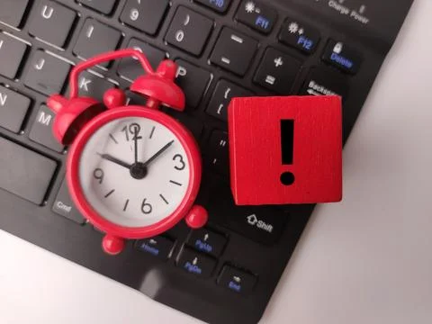 A red mini alarm clock sits atop a black computer keyboard alongside a red .. Stock Photos
