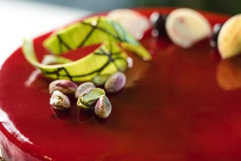 Red mirror half glazed cake with pistachio and chocolate on top Stock Photos