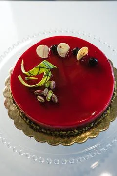 Red mirror half glazed cake with pistachio and chocolate on top Stock Photos