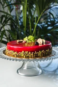 Red mirror half glazed cake with pistachio and chocolate on top Stock Photos