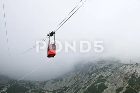 Red mountain cableway car in clouds and fog Stock Photos