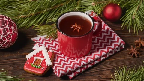 Red mug of fruit tea and Christmas decorations on wooden table with fir tree Stock Footage 122764931