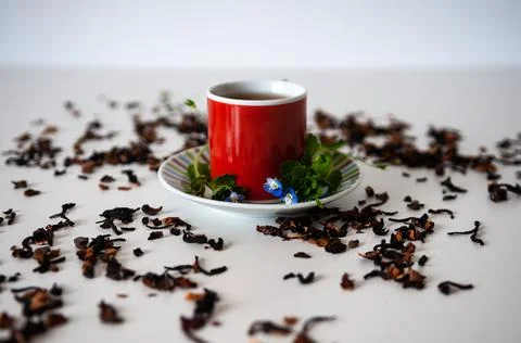 Red mug on a white table with leafs and flowers and white background Stock Photos