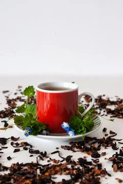Red mug on a white table with leafs and flowers and white background Stock Photos