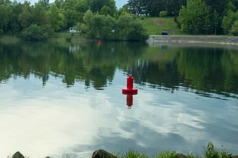 Red navigation buoy floating on the calm water surface of a scenic river wi.. Stock Photos