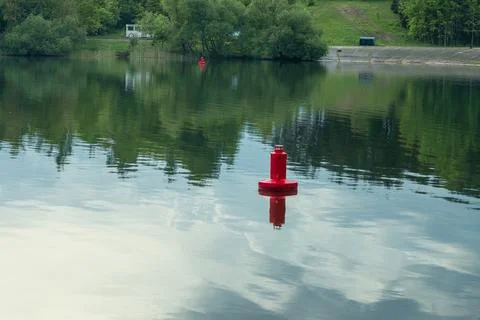 Red navigation buoy floating on the calm water surface of a scenic river wi.. Stock Photos